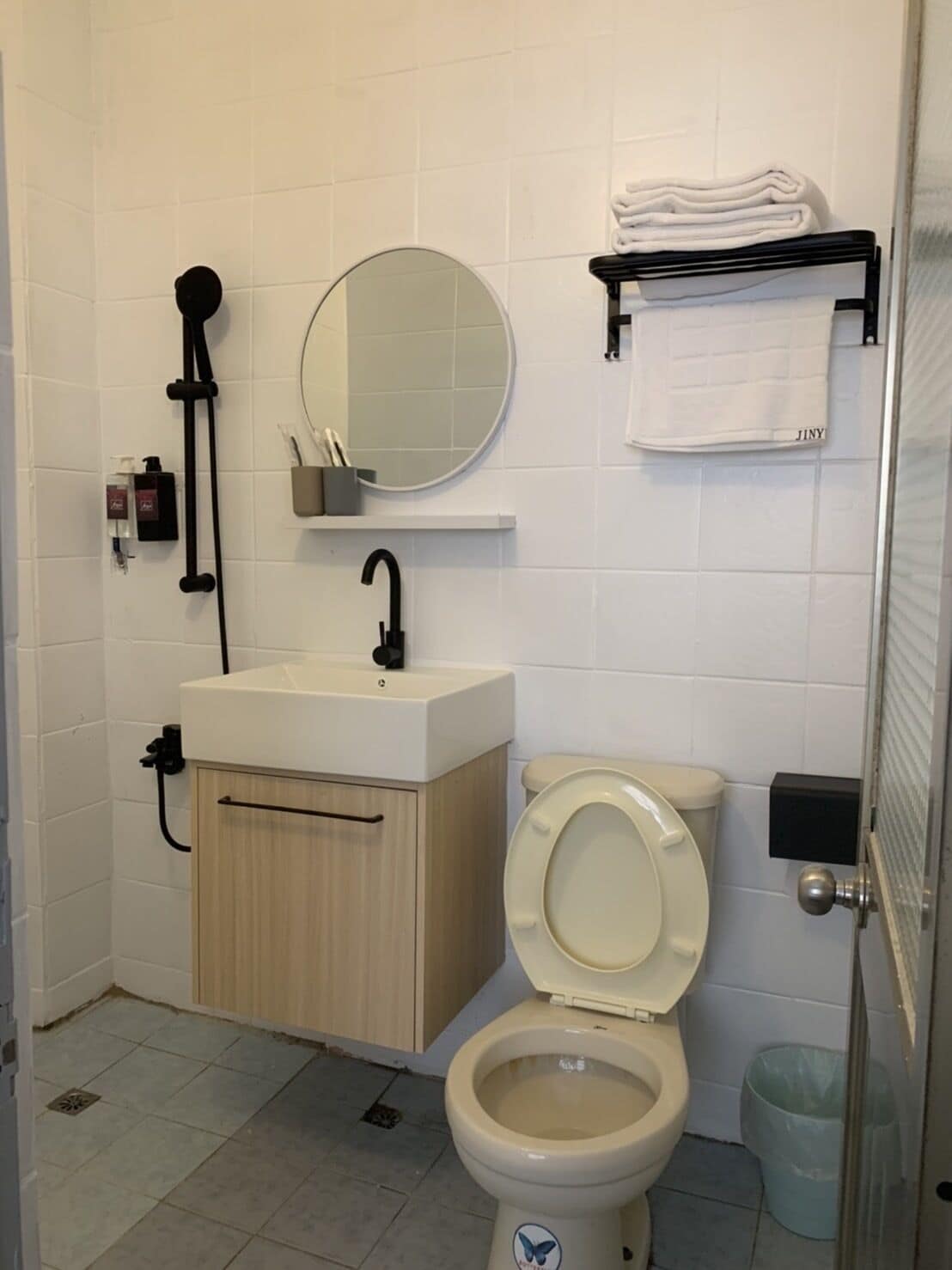 A bathroom with a toilet, sink, mirror, and towel rack.
