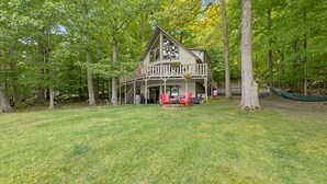 Een chalet met een veranda, buitenmeubels en een hangmat.
