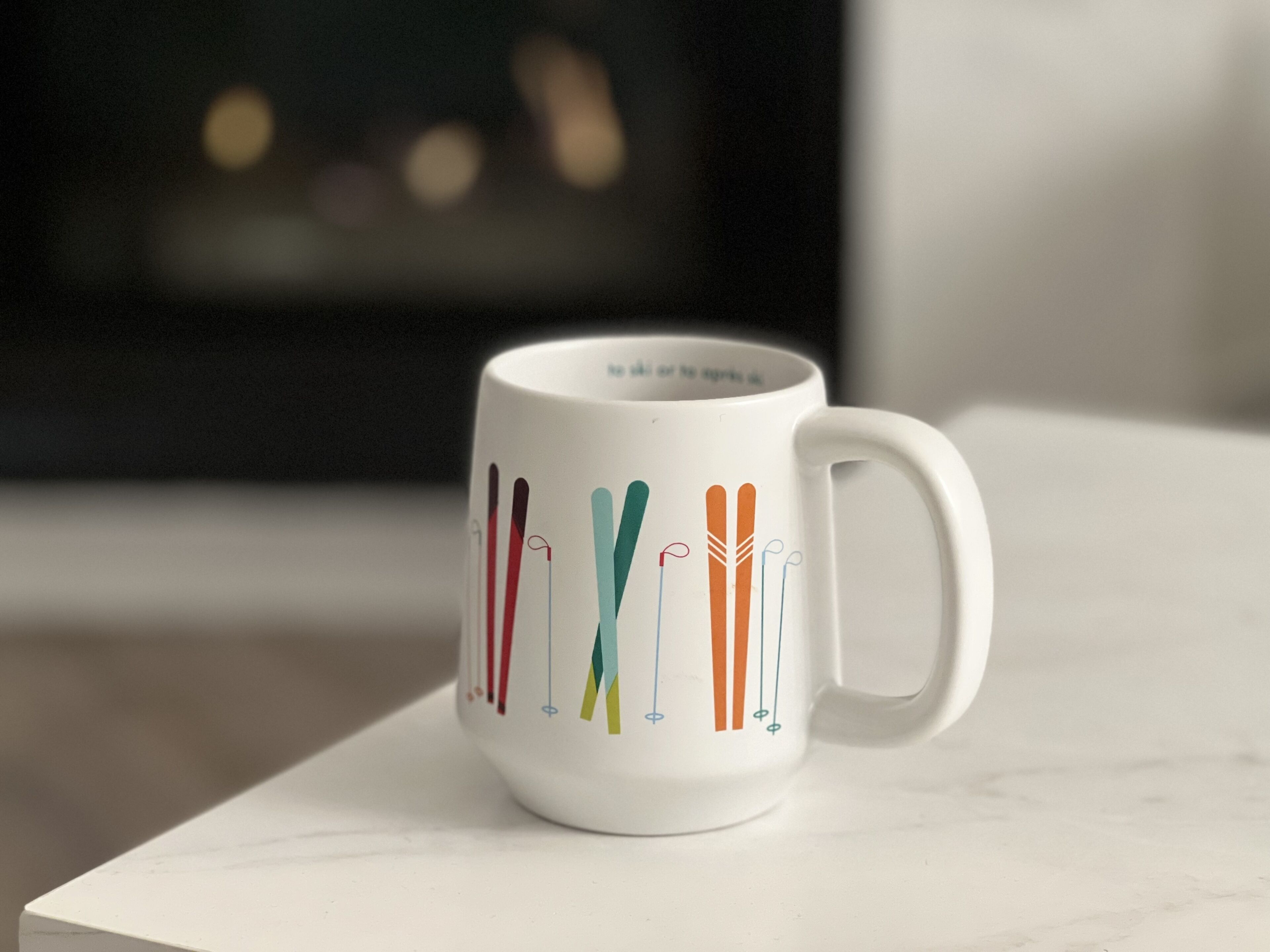 A white ceramic mug with ski designs on a white surface.