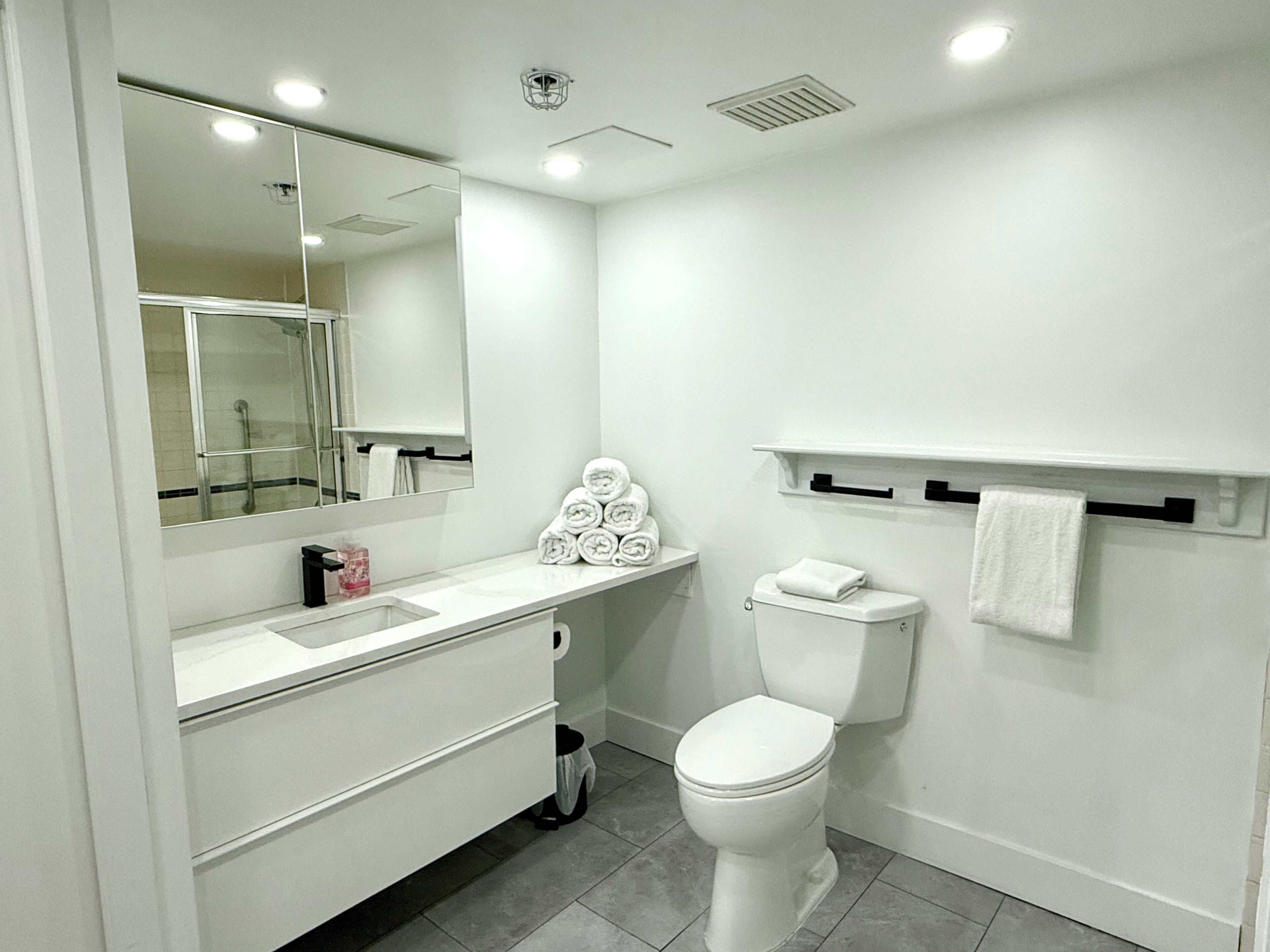 A modern bathroom with a white sink, mirror, and toilet.