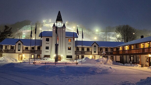 A hotel with a central tower, multiple balconies, and snow-covered surroundings.