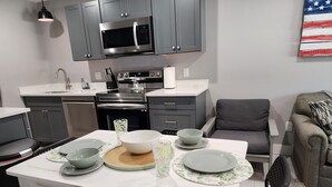 A modern kitchen with grey cabinets, a microwave, an oven, and a dining table set with bowls and plates.