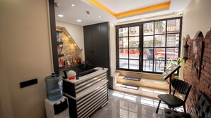 A reception area with a water dispenser, a fan, a counter, and a view of the street through a large window. - Mila Suites Taksim (Istanbul)