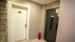 A hallway with a white door labeled '302', a dark door with a window, and a red fire extinguisher. - Mila Suites Taksim (Istanbul)