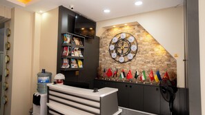 A reception area with a stone wall, a clock, a water dispenser, and a row of flags. - Mila Suites Taksim (Istanbul)