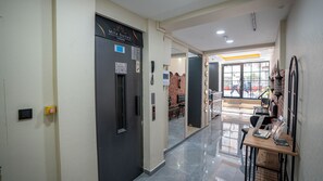 A hotel hallway with a reception desk, a seating area with chairs, and a brick wall. - Mila Suites Taksim (Istanbul)