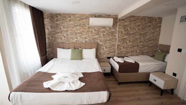 A hotel room with a stone-patterned wall, a large bed with a brown headboard, a smaller bed, a bedside table, a nightstand, and a wall-mounted air conditioning unit. - Mila Suites Taksim (Istanbul)