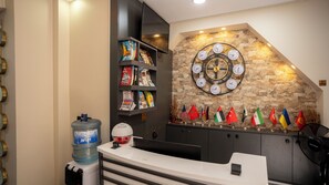 A reception area with a water dispenser, a clock with multiple time zones, and a display of international flags. - Mila Suites Taksim (Istanbul)