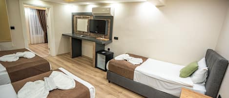 A hotel room with two beds, a desk, a mirror, and a small refrigerator.