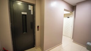 A hallway with a door marked '301' and a digital elevator display.