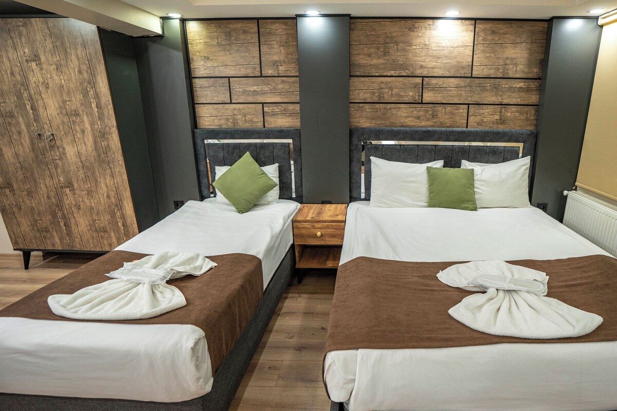 A hotel room with two beds, wooden headboards, a large mirror, and a radiator.