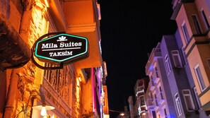 A sign for 'Mila Suites' with a neon outline, attached to a building with ornate architecture and a dark night sky in the background. - Mila Suites Taksim (Istanbul)