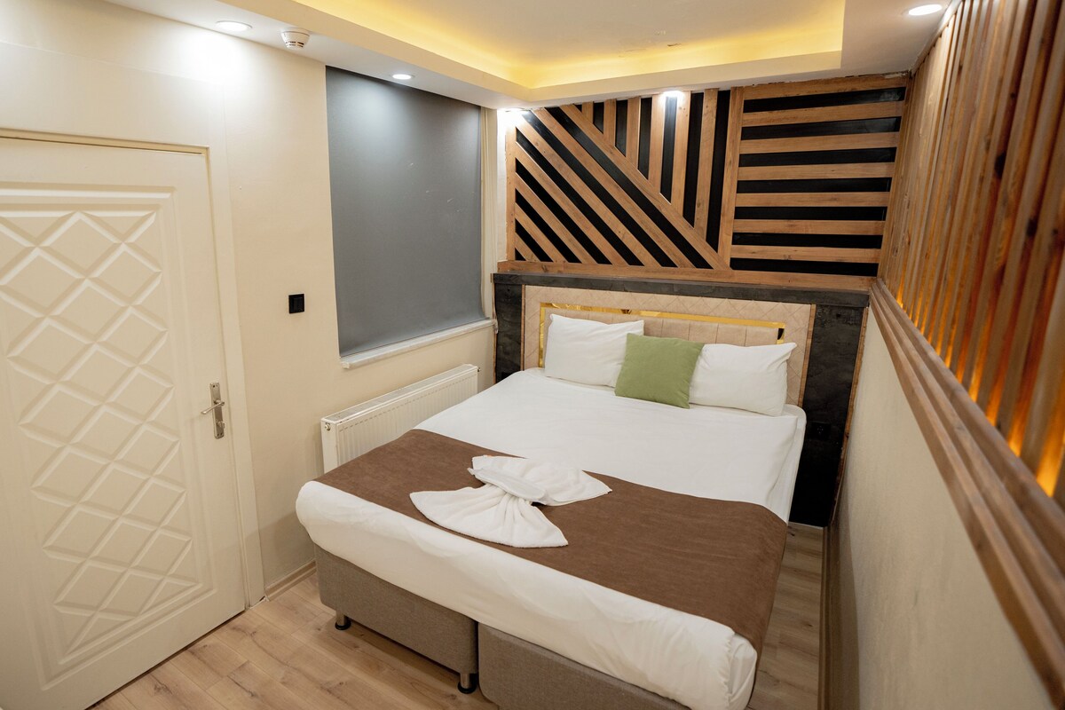 A hotel room with a bed, a door, and a wall with a geometric pattern.
