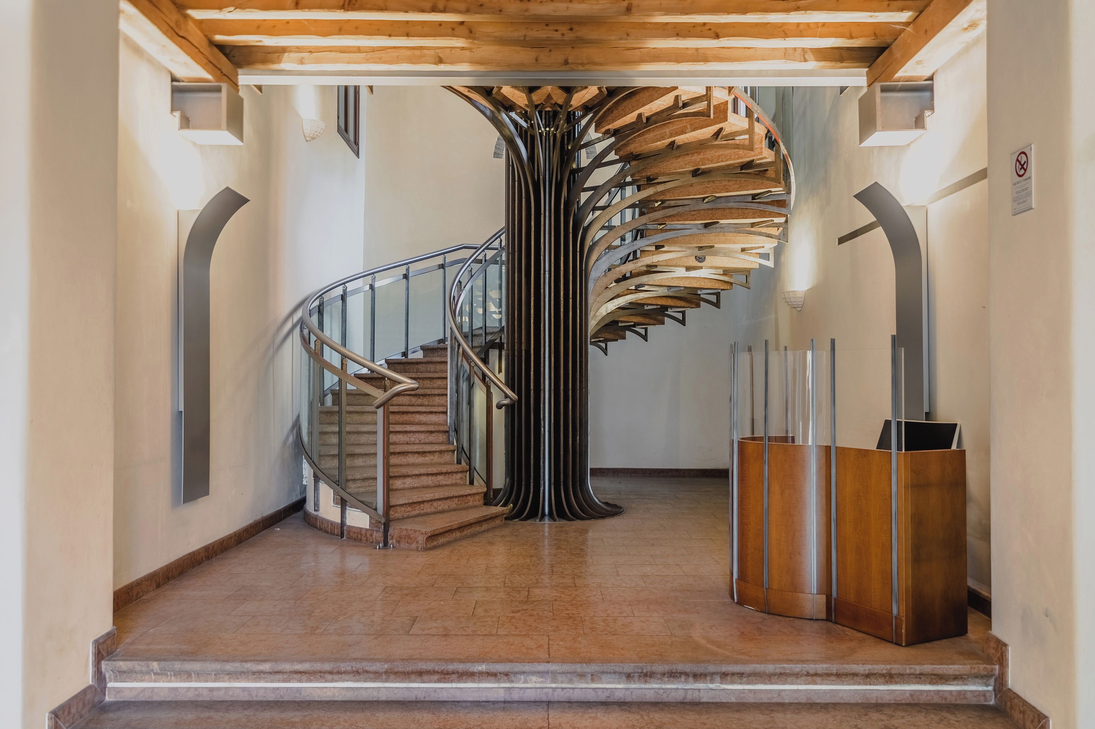 Una escalera en espiral con detalles de madera y barandillas de metal, que conduce a un piso superior.