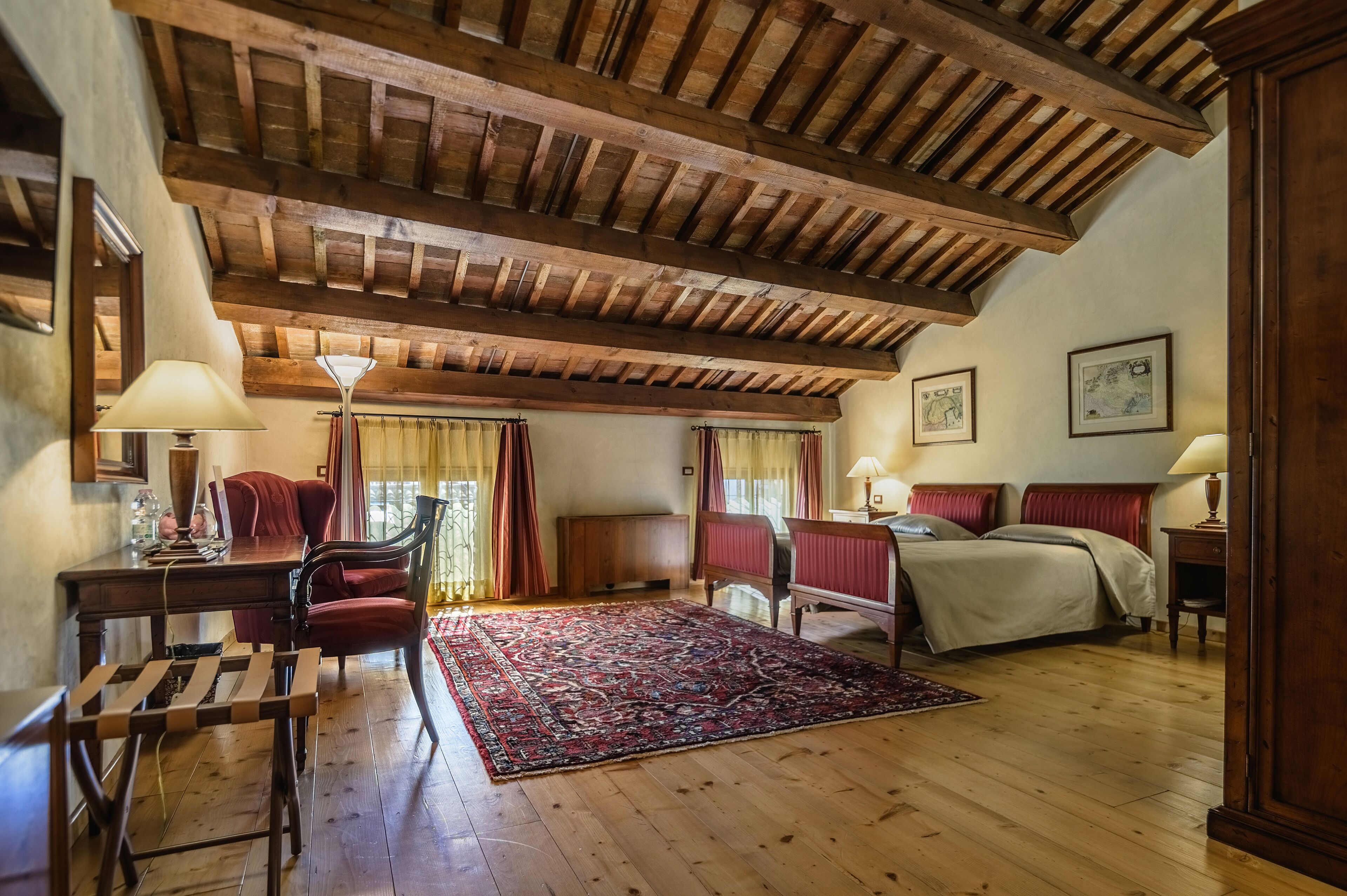 Una habitación con techo de madera, una cama, un escritorio y una silla.