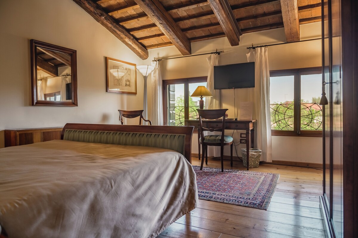 Une chambre à coucher comprenant un lit, un bureau, une chaise, un téléviseur et une vue sur l’extérieur.