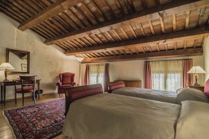 Una habitación con techo de madera, dos camas, una silla, un escritorio y una alfombra.