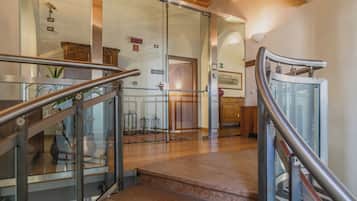 A modern interior with a glass door entrance, wooden flooring, and metal railings.