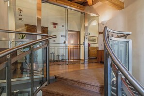 Una escalera con barandillas de vidrio que lleva a una habitación con pisos y techo de madera.