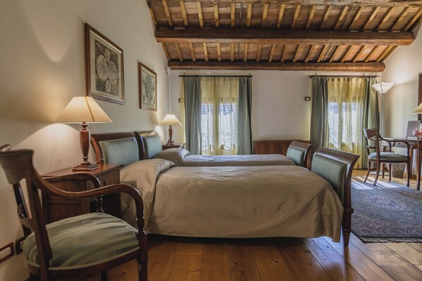 A traditional room with two beds, wooden furniture, and a rustic ceiling. - Le Camere di Palazzo Bortolan (Treviso)