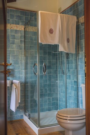 Casa de banho com cabine de duche em vidro, sanita e lavatório.