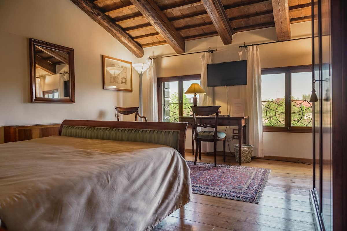 Ein Schlafzimmer mit Bett, Schreibtisch, Stuhl, Fernseher und Blick ins Freie.