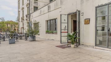 A building with a ground-level entrance, outdoor seating area, and potted plants.