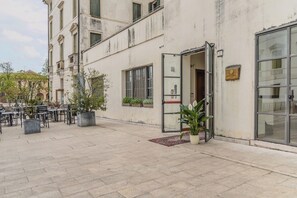 Un edificio con entrada a nivel de calle, zona de estar al aire libre y plantas en macetas.