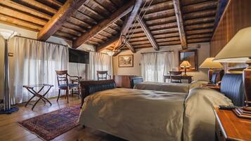 Un dormitorio acogedor con vigas de madera, una cama grande, dos sillas, un escritorio y una lámpara.