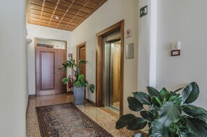 A hallway with a wooden ceiling, a patterned rug, and potted plants. - Le Camere di Palazzo Bortolan (Treviso)