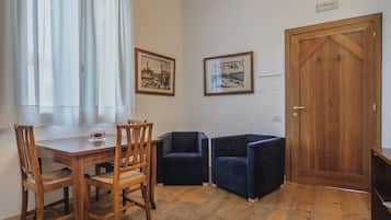A room with a wooden dining table, two chairs, a wooden door, and two framed pictures on the wall.