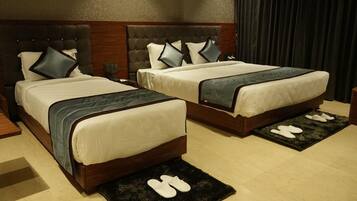 A hotel room with two beds, a wooden headboard, and a dark curtain.