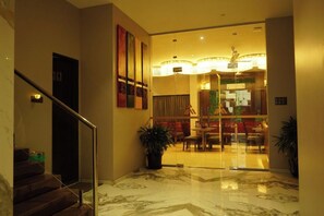 A hotel lobby with a marble floor, a staircase, and a dining area with chairs and tables. - Alaukik Hotel (Rahata)