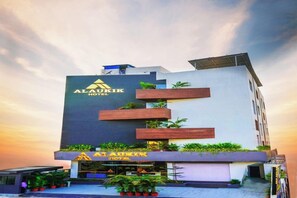 Un moderno edificio de hotel con un logotipo destacado, varios balcones y un techo plano.