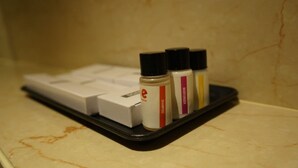 Un baño con una bandeja negra que contiene botellas de champú y un dispensador de jabón blanco.