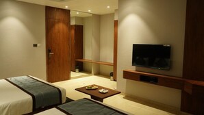 Habitación de hotel con cama, televisor montado en la pared, una mesita con un plato de comida y un espejo.