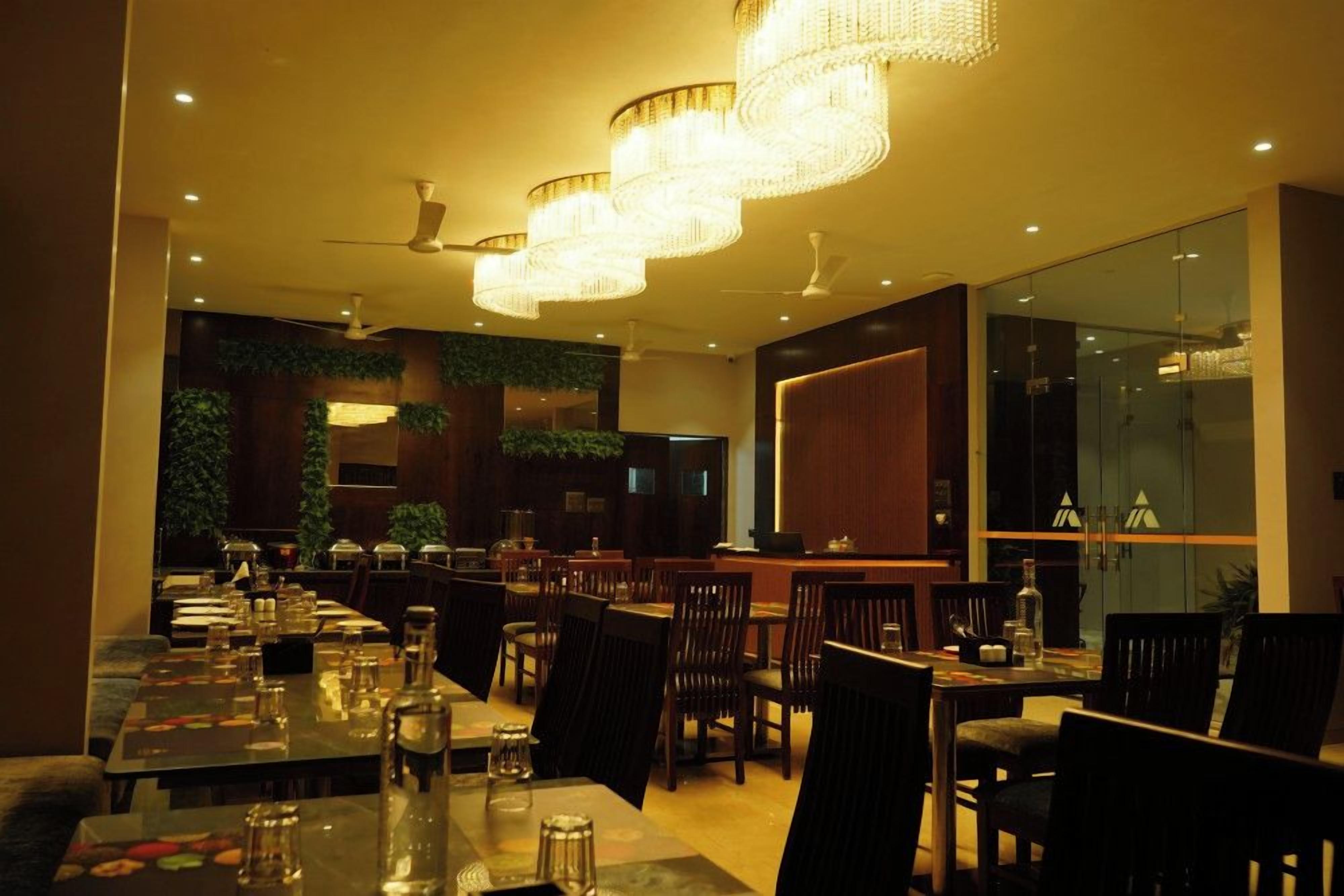 A restaurant with multiple dining tables and chairs, ceiling fans, and decorative lighting fixtures.