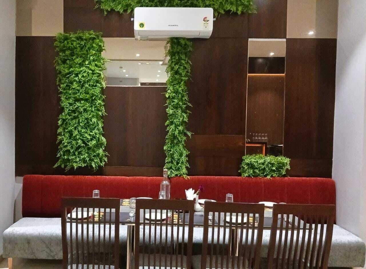 Un comedor con un banco acolchado rojo, una mesa con sillas y un aire acondicionado instalado en la pared.