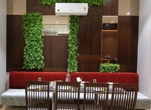 Un comedor con un banco acolchado rojo, una mesa con sillas y un aire acondicionado instalado en la pared.