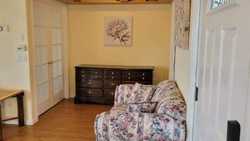 A cozy living room with a floral sofa, a wooden coffee table, and a dark wooden dresser.