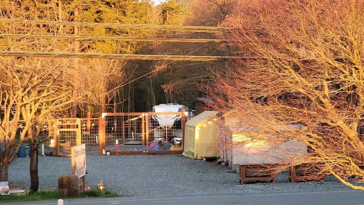 A fenced area with a covered structure, possibly a storage or utility building, and a vehicle parked nearby.