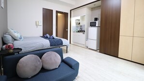 Un dormitorio moderno con una cama, un sofá y una kitchenette al fondo.