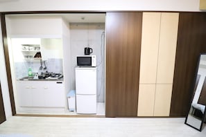 Cozinha compacta com micro-ondas, mini-geladeira e pia.