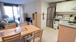 Un espacio habitable compacto con zona de comedor, kitchenette y sofá cerca de una ventana.