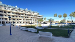 Un patio de hotel con piscina, mobiliario exterior y palmeras.