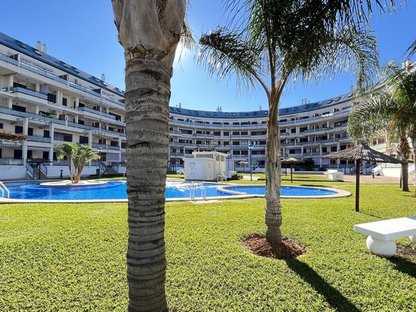 Ein Hotel mit mehreren Balkonen, einem Pool und Palmen.