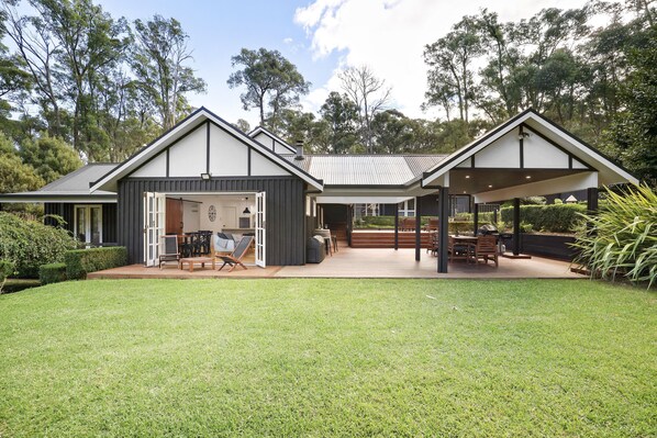 Une maison moderne dotée d’un patio couvert, d’une pelouse et d’un garage.
