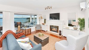 Un salon moderne avec une cheminée, un téléviseur et une vue sur la mer.