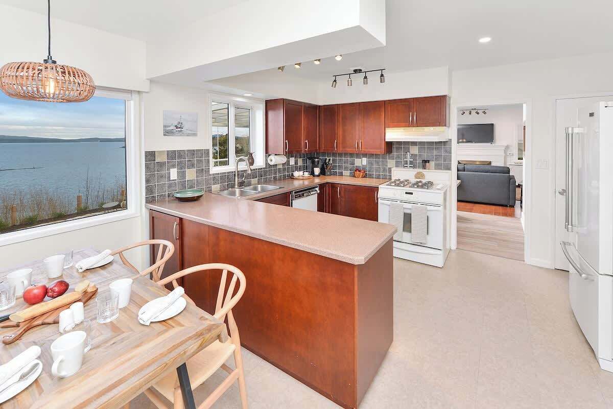 A modern kitchen with a central island, wooden cabinets, and a view of the water.