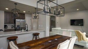 A modern kitchen with a central island, stainless steel appliances, and pendant lighting. - Gourmet Kitchen with Large Dining Table, Quiet Neighborhood, Close to COTA and Airport (Austin)